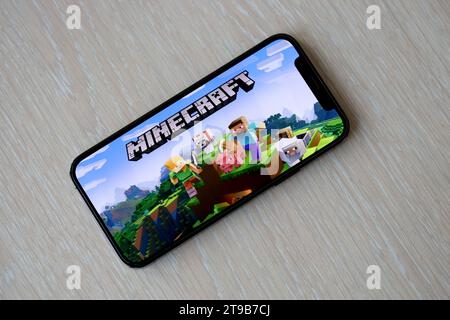 Minecraft mobiles iOS-Spiel auf dem iPhone 15 Smartphone-Bildschirm auf Holztisch während des mobilen Gameplays. Mobiles Gaming und Entertainment auf einem tragbaren Gerät Stockfoto