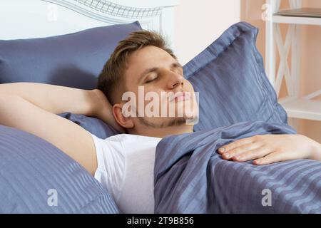 Süßer junger Mann, der morgens im Bett schläft Stockfoto