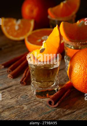 Süßer Orangenlikör mit Zimt und frischem Obst auf einem alten Holztisch. Stockfoto