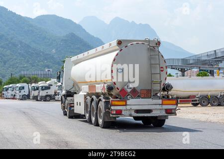 Parken einer Reihe von Lkw mit Kraftstofftanks vor einem Lager und Lagerung von riesigen Tanks mit Rohmaterialbehältern Stockfoto