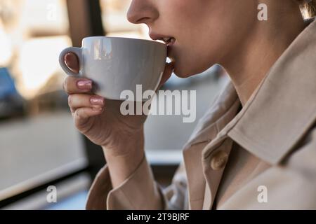Zugeschnittene Nahaufnahme einer jungen Frau mit perfekter Haut, die Kaffee im Café trinkt, eine Tasse Cappuccino Stockfoto