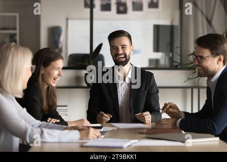 Positiv aufgeregtes Business-Team und junger männlicher Leiter, der Spaß hat Stockfoto
