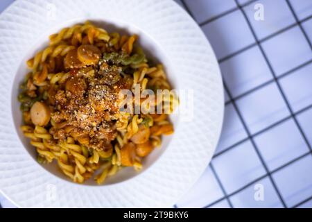 Fusilli-Pasta mit Wurst- und Tomatensauce in weißer Schale. Spirale- oder Fusilli-Pasta mit Tomatensauce und Käse - italienische Küche Stockfoto