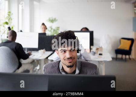 Lächelnder junger Mann im Büro, der wegblickt Stockfoto