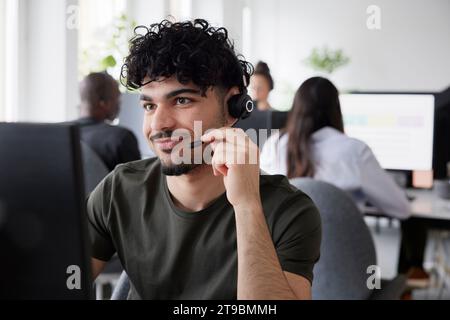 Mann, der im Büro ein Headset mit einem Desktop-PC trägt Stockfoto