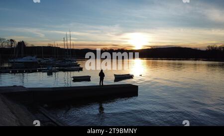 Boote und Docks bei Sonnenaufgang spiegeln sich am Lago Maggiore in Italien. Farbtöne im Schatten der Nacht Stockfoto