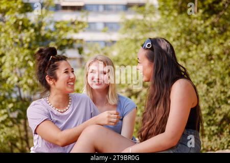 Drei junge Freundinnen sitzen zusammen und unterhalten sich Stockfoto