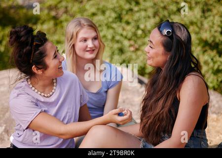 Drei junge Freundinnen sitzen zusammen und unterhalten sich Stockfoto