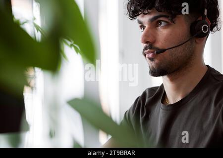 Junger Mann, der ein Headset trägt und wegblickt Stockfoto