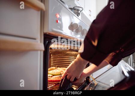 Frau, die Essen für eid al-fitr aus dem Ofen nimmt Stockfoto