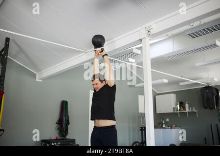 Tiefwinkelansicht eines jungen Mannes, der im Fitnessstudio mit Kettlebell trainiert Stockfoto