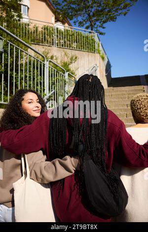 Porträt einer lächelnden jungen Frau, die mit Freunden auf der Treppe aufsteigt Stockfoto