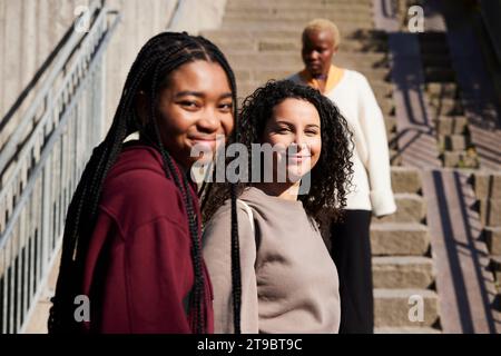 Porträt glücklicher junger multirassischer Freunde gegen Treppe Stockfoto