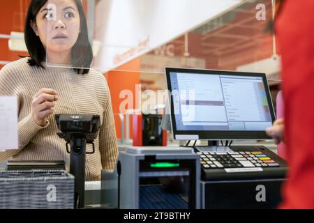 Junge Kundin, die mit der Kassiererin beim Checkout im Supermarkt spricht Stockfoto