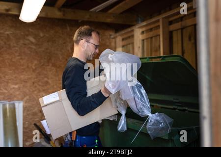Seitenansicht eines männlichen Arbeiter, der Kunststoff- und Pappabfälle in den Mülltonnen wirft Stockfoto