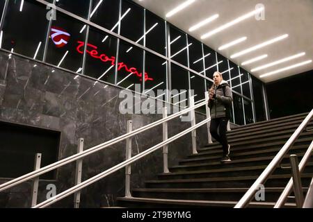 Belgrad, Serbien, 20. November 2023: Teenager geht die U-Bahn-Treppe hinunter, mit reflektierenden Innenleuchten und Belgrader Kaufhaus-Schild Stockfoto