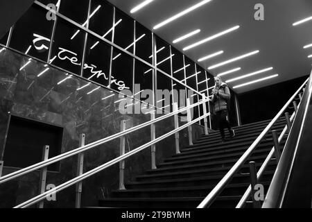 Belgrad, Serbien, 20. November 2023: Teenager geht die U-Bahn-Treppe hinunter, mit reflektierenden Innenleuchten und Belgrader Kaufhaus-Schild Stockfoto