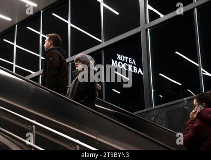 Belgrad, Serbien - 20. November 2023: Menschen, die die U-Bahn-Rolltreppe hinaufsteigen, mit reflektierender Innenbeleuchtung und Hotel Moskva-Schild in der Nacht Stockfoto