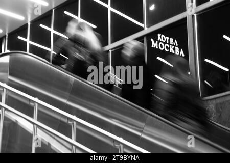 Belgrad, Serbien - 20. November 2023: Abstrakte, unscharfe Menschen, die die U-Bahn-Treppe hinaufsteigen, mit Reflexen im Innenraum und dem Schild für das Hotel Moskau in kyrill Stockfoto