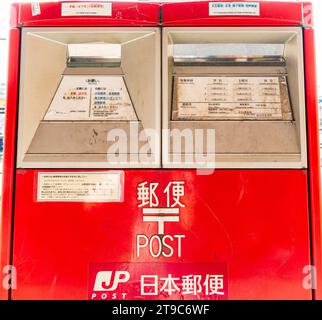 Nahaufnahme eines doppelten japanischen roten Briefkastens, mit einer Seite für Briefe und Postkarten und einer anderen für internationale Post. Stockfoto