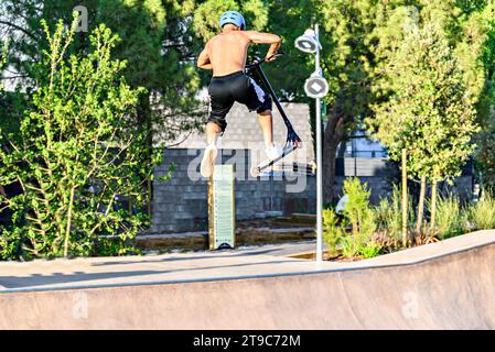 Junger Mann, der Motorroller (Freestyle Scooter) im neuen Skatepark im zentralen Park von Igualada, Barcelona, Spanien, praktiziert Stockfoto