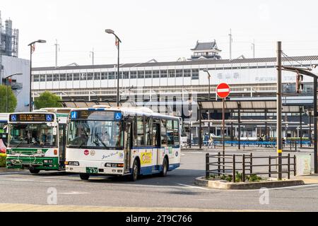 Busbahnhof, Terminal vor dem JR Fukuyama Zug und shinkansen Bahnhof mit Schloss dahinter an einem sonnigen Frühlingstag. Zwei Busse fahren ab. Stockfoto