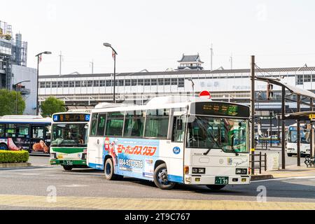 Busbahnhof, Terminal vor dem JR Fukuyama Zug und shinkansen Bahnhof mit Schloss dahinter an einem sonnigen Frühlingstag. Zwei Busse fahren ab. Stockfoto