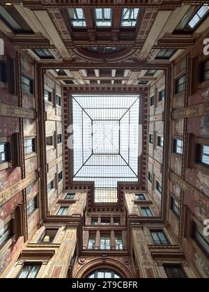 Fenster im Spektrum: Ein faszinierender Blick nach oben fängt das lebendige Innere eines Gebäudes ein, in dem jede Wand mit Fenstern geschmückt ist, und sogar die Stockfoto