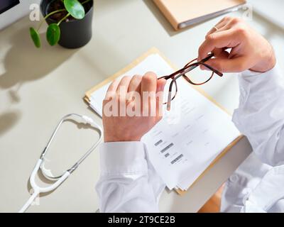 Anonymer männlicher Arzt in einem weißen Kleid, der medizinische Unterlagen in einer Klinik ausfüllt Stockfoto