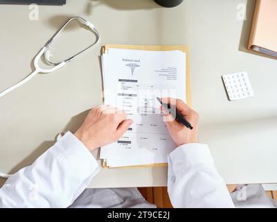 Anonymer männlicher Arzt in einem weißen Kleid, der medizinische Unterlagen in einer Klinik ausfüllt Stockfoto