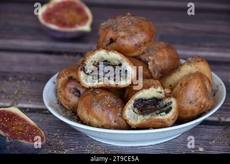 Hausgemachte Profiteroles-Kuchen mit Kakaocreme-Füllung und Schokoladenchips. Choux-Gebäck, Creme-Puffs auf Teller, Feigenhälften auf Holztisch. Stockfoto