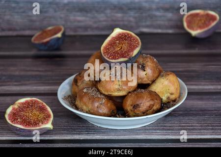 Köstliche hausgemachte Profiteroles-Kuchen mit Kakaocreme-Füllung und Schokoladenchips. Choux-Gebäck, Creme-Puffs auf Teller, Feigenhälften, Holztisch. Stockfoto