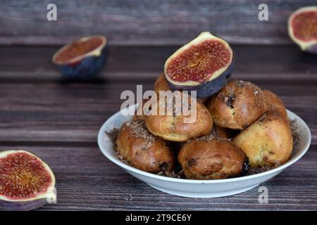 Köstliche hausgemachte Profiteroles-Kuchen mit Kakaocreme-Füllung und Schokoladenchips. Choux-Gebäck, Creme-Puffs auf Teller, Feigenhälften, Holztisch. Stockfoto