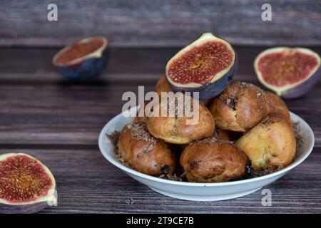 Köstliche hausgemachte Profiteroles-Kuchen mit Kakaocreme-Füllung und Schokoladenchips. Choux-Gebäck, Creme-Puffs auf Teller, Feigenhälften, Holztisch. Stockfoto