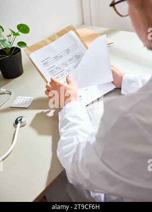 Männlicher Arzt, der die Papiere des Patienten in einem Krankenhaus durchsucht Stockfoto