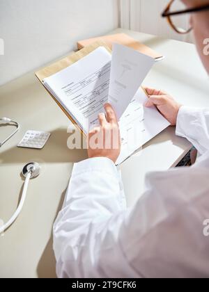 Männlicher Arzt, der die Papiere des Patienten in einem Krankenhaus durchsucht Stockfoto