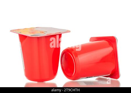 Zwei Obstjoghurts in Plastikbehältern, Nahaufnahme, isoliert auf weiß. Stockfoto