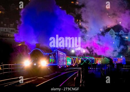 Kingswear, Devon, Großbritannien. November 2023. Der Christmas Train of Lights auf der Dartmouth Steam Railway, der zwischen dem 24. November und dem 30. Dezember 2023 verkehrt, fährt von der Kingswear Station in Devon auf dem Weg nach Paignton ab. Die Wagen und Dampflokomotiven des Festdienstes sind innen und außen mit farbigen Lichtern beleuchtet. Bildnachweis: Graham Hunt/Alamy Live News Stockfoto