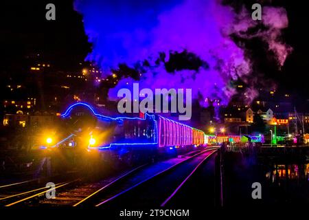 Kingswear, Devon, Großbritannien. November 2023. Der Christmas Train of Lights auf der Dartmouth Steam Railway, der zwischen dem 24. November und dem 30. Dezember 2023 verkehrt, fährt von der Kingswear Station in Devon auf dem Weg nach Paignton ab. Die Wagen und Dampflokomotiven des Festdienstes sind innen und außen mit farbigen Lichtern beleuchtet. Bildnachweis: Graham Hunt/Alamy Live News Stockfoto