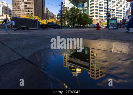 Ein neues Hochhaus spiegelt sich in einer Pfütze auf dem Campus des Martius Park in Detroit, USA, wider Stockfoto