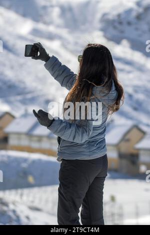 Latina-Frau mittleren Alters macht mit ihrem Smartphone ein Selfie in den Bergen der sierra nevada, im Skigebiet granada Stockfoto