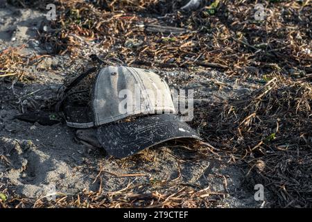 Strand in Norditalien nach einem heftigen Sturm. Kappe, Hut, Plastik und Dosen wurden zusammen mit Algen vom Meer zurückgebracht. Verschmutzung und Abfall am Strand. Stockfoto