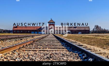 Neben einem Industriegebäude ist ein Bahngleis mit dem Eingang zum Konzentrationslager Auschwitz Birkenau im Vordergrund zu sehen Stockfoto