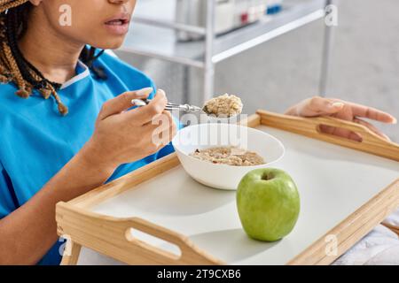 Zugeschnittene Ansicht einer jungen afroamerikanischen Frau, die ihr Frühstück im Krankenhausbett, Gesundheitswesen Stockfoto