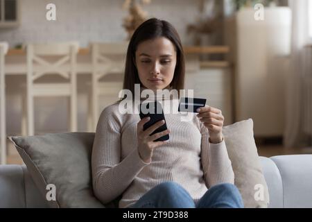 Attraktive Frau, die Handy und Karten im Internet kauft Stockfoto