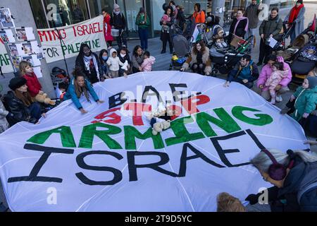 London, Großbritannien. November 2023. Eltern, Babys und Kinder umgeben einen Fallschirm, der mit der Aufschrift "BAE Stop Ararming Israel" bemalt ist, während eines Protestes der Eltern für Palästina innerhalb und außerhalb eines Gebäudes, in dem sich die Büros des Rüstungsunternehmens BAE Systems befinden, um einen Waffenstillstand in Gaza zu fordern und die britische Regierung den Waffenverkauf einzustellen nach Israel. Eltern protestierten in Solidarität mit palästinensischen Familien in Gaza, wo seit dem 7. Oktober 2023 nach Angaben des palästinensischen Gesundheitsministeriums über 5.800 Kinder bei israelischen Luftangriffen getötet wurden. Quelle: Mark Kerrison/Alamy Live News Stockfoto