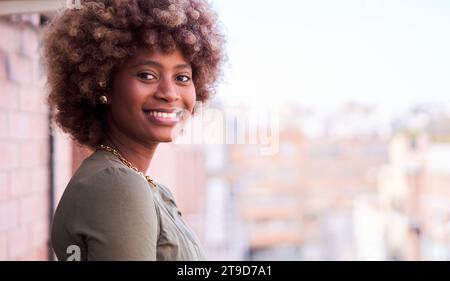 Fröhliches Porträt einer afro-karibischen jungen Frau, die lächelnd in die Kamera schaut. Stockfoto