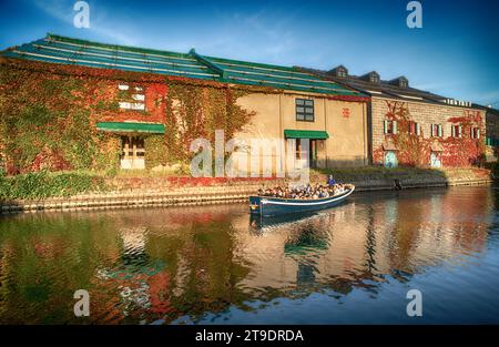 Touristenboot Segeln im Otaru Kanal am hellen Tag und farbenfrohen Herbst, Hokkaido, Japan Stockfoto