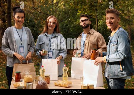 Porträt von Freiwilligen, die Lebensmittel am Tisch im Park packen Stockfoto