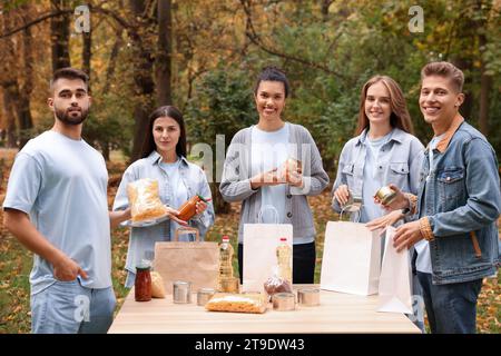 Porträt von Freiwilligen, die Lebensmittel am Tisch im Park packen Stockfoto
